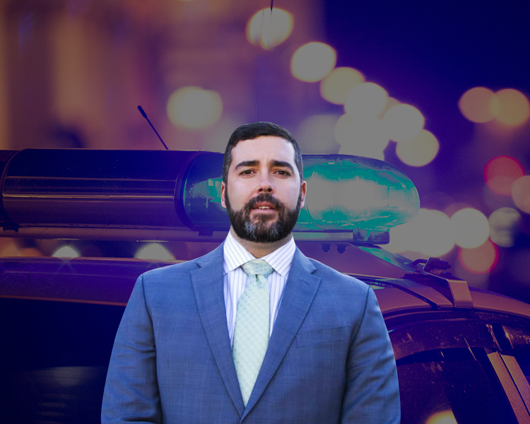 Profile photo of Rudy 'Glynn' Vrba, with a background photograph focused on the sirens of a police car against a blurry backdrop of street lights.