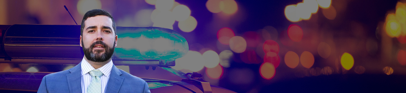 Profile photo of Rudy 'Glynn' Vrba, with a background photograph focused on the sirens of a police car against a blurry backdrop of street lights.